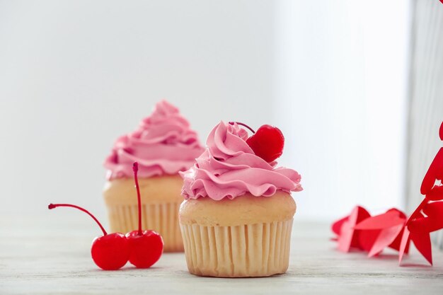 Deliciosos cupcakes de vainilla y cerezas en la mesa