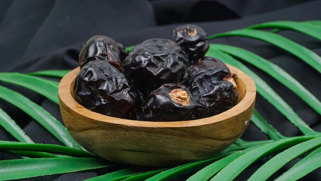 Deliciosos dátiles ajwa kurma nabi o dátiles del profeta Kurma Ajwa sobre textura de tela negra