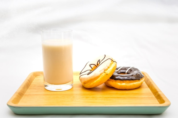 Deliciosos donuts assados com um copo de leite na bandeja de madeira
