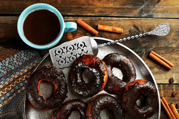 Deliciosos donuts com cobertura de chocolate e xícara de café na mesa close-up