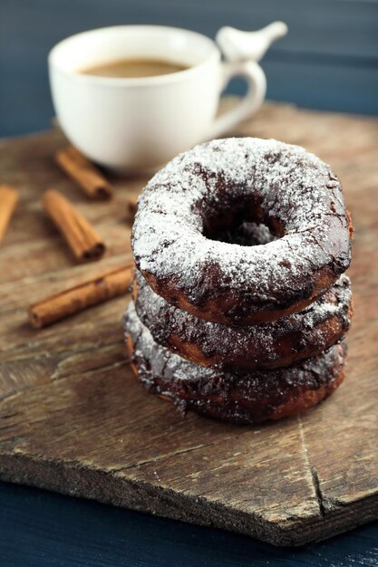 Deliciosos donuts con glaseado de chocolate y una taza de café en la mesa de cerca