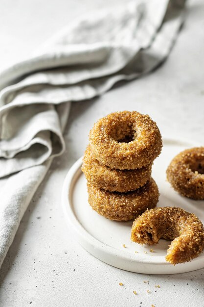 Deliciosos donuts revestidos de açúcar em um prato fundo texturizado branco com guardanapo