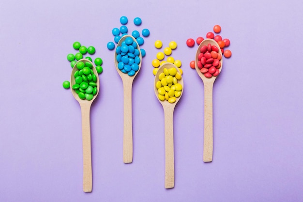 deliciosos dulces coloridos en cuchara en fondo coloreado decoración de confitería vista superior con espacio de copia