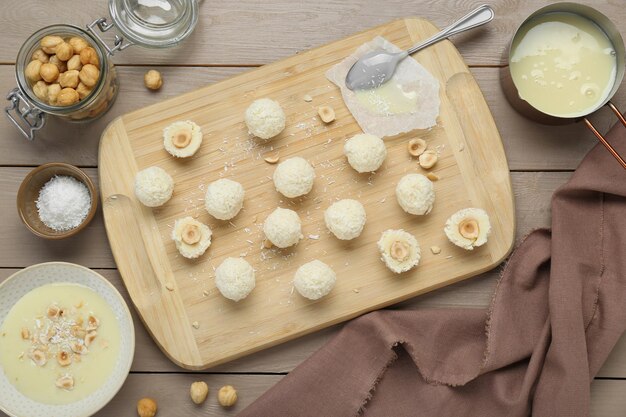 Foto deliciosos dulces con copos de coco, avellanas e ingredientes en una mesa de madera plana