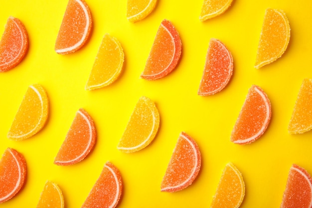 Deliciosos dulces de mermelada de naranja y limón sobre fondo amarillo, plano laical