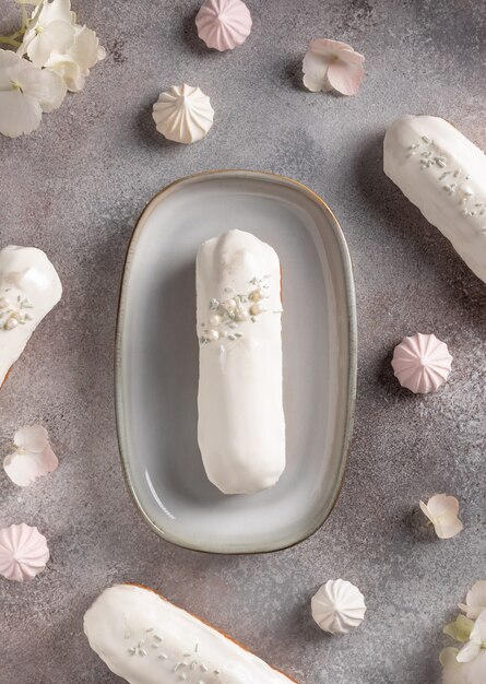 Deliciosos éclairs de chocolate branco em fundo de flores com doces. Sobremesa tradicional francesa. imagem vertical