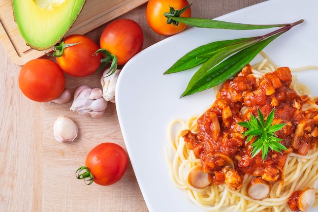 Deliciosos espaguetis servidos en un plato blanco en la mesa de madera