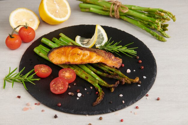 Deliciosos espárragos verdes y salmón ahumado en rodajas en un plato rústico