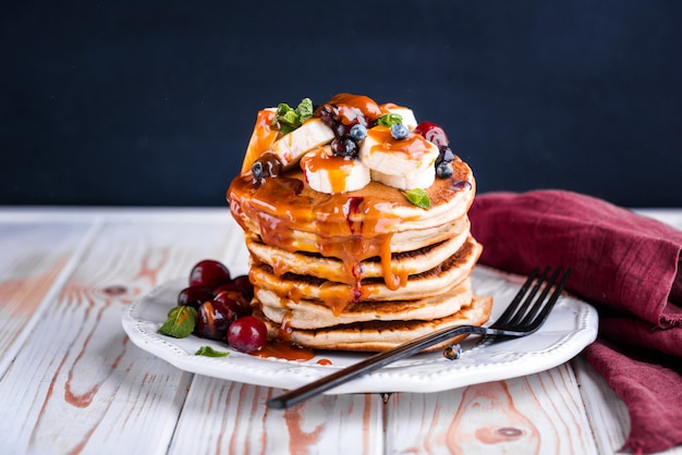 Deliciosos y exuberantes panqueques con frutas frescas y bayas, servidos con caramelo salado.