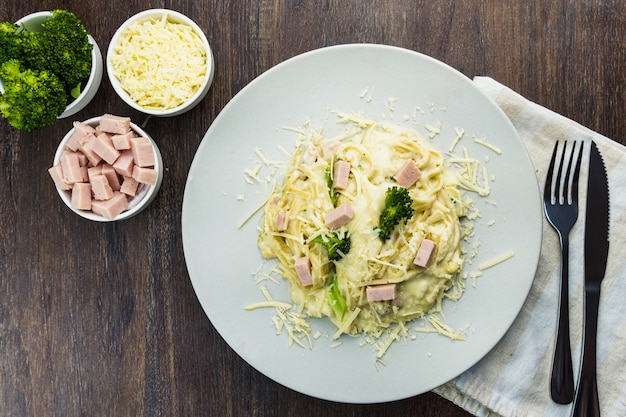 Deliciosos Fettuccine con salsa blanca, brócoli, dados de pechuga de pavo y queso rallado. Enfoque selectivo. Vista superior.