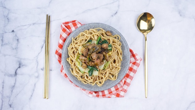 Deliciosos fideos de pollo indonesios llamados mie ayam cubiertos con carne de pollo y vegetales verdes Fideos populares en Indonesia