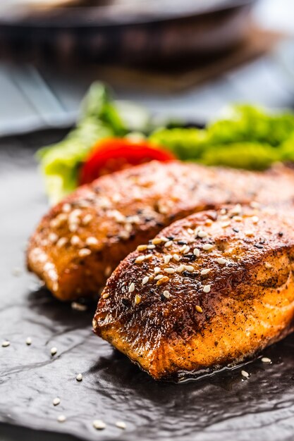 Foto deliciosos filés de salmão assados grelhados ou bifes com tomate gergelim e salada de alface.