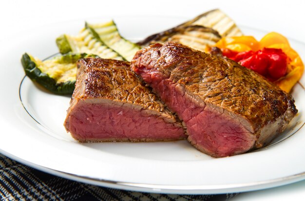 Deliciosos filetes de carne en un plato blanco con verduras a la parrilla