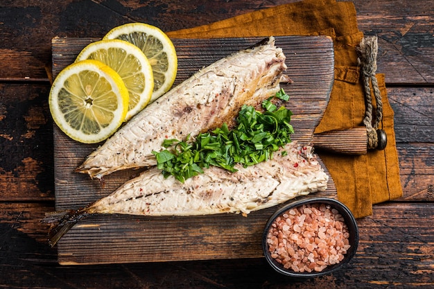 Foto deliciosos filetes de cavala assados com verduras alho e limão em tábua de madeira fundo de madeira vista de cima