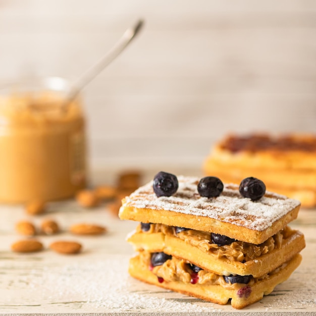 Deliciosos gofres con pasta de maní y arándanos sobre un fondo claro