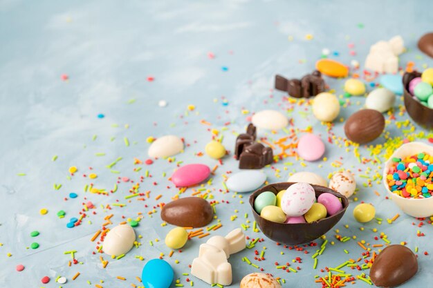 Deliciosos huevos de Pascua de chocolate, conejos y dulces sobre un fondo de hormigón azul Composición de Pascua