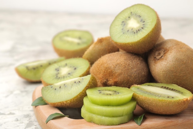 Deliciosos lotes maduros de kiwi y kiwi cortados en una tabla sobre un fondo de hormigón ligero