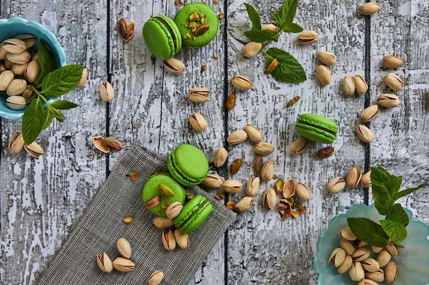 Foto deliciosos macarrões com sabor a pistache em fundo de madeira cinza vintage com folhas de hortelã