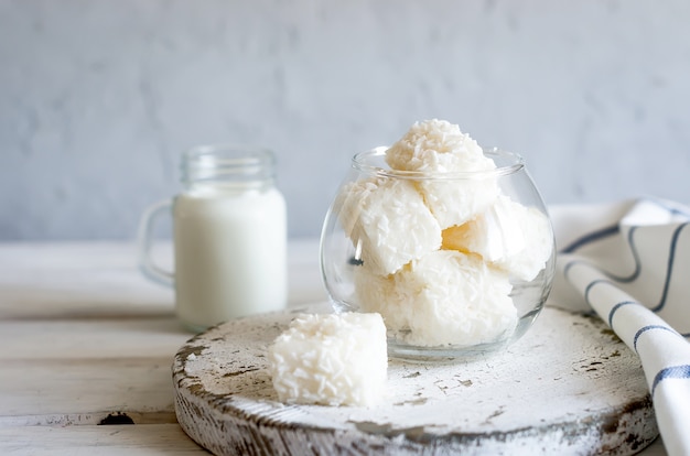 Deliciosos malvaviscos blancos o dulces en copos de coco y taza de leche