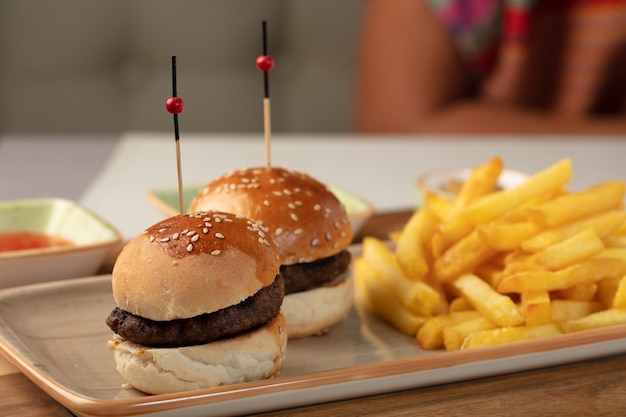 Deliciosos mini hambúrgueres caseiros servidos com molho e batata frita