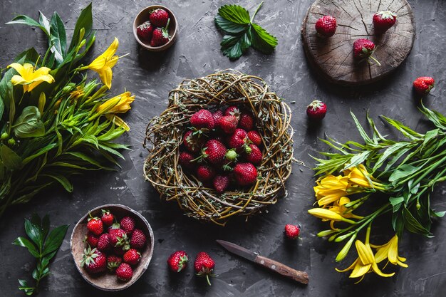 Deliciosos morangos com flores amarelas sobre uma superfície cinza escura em uma grinalda vintage. Comida saudável, frutas