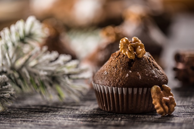 Deliciosos muffins de chocolate navideños espolvoreados con azúcar en polvo y nuez encima.