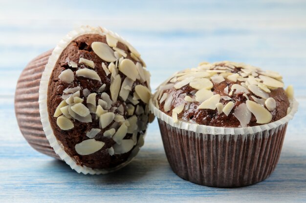 Deliciosos muffins de chocolate doce, com pétalas de amêndoa sobre uma mesa de madeira azul.