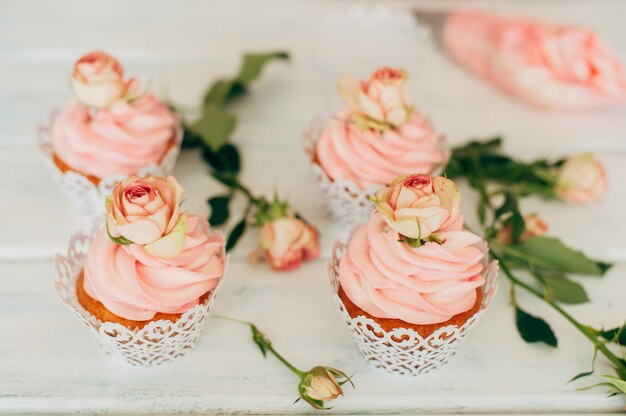 Deliciosos muffins saborosos com um creme rosa decorado com rosas reais