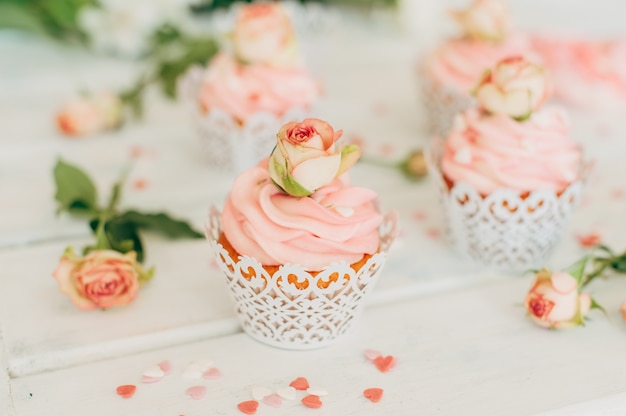 Deliciosos muffins sabrosos con una crema rosa decorada con ros real