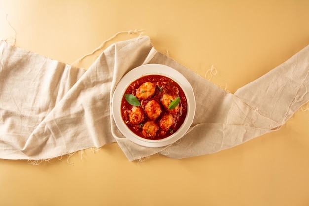 Deliciosos ñoquis con salsa roja y albahaca en vista superior de olla de cerámica artesanal