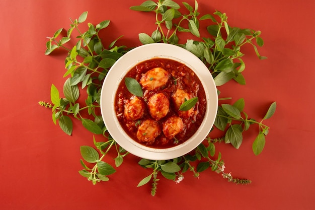 Deliciosos ñoquis con salsa roja y albahaca en vista superior de olla de cerámica artesanal