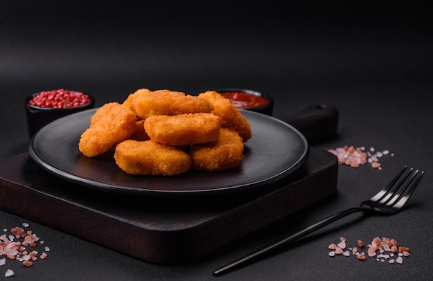 Deliciosos nuggets de frango crocantes frescos em um fundo escuro de concreto