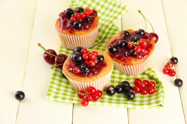 Deliciosos panecillos con bayas en la mesa de madera blanca