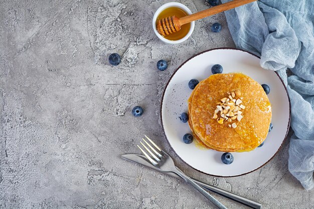 Deliciosos panqueques caseros con miel y arándanos. Sabroso desayuno con crepes. Vista superior