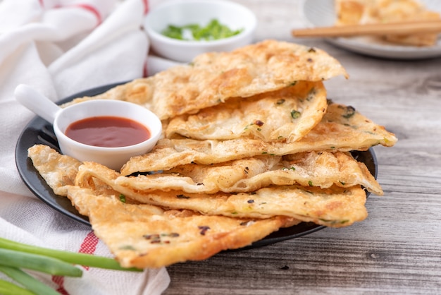 Deliciosos panqueques de cebolleta en una placa negra