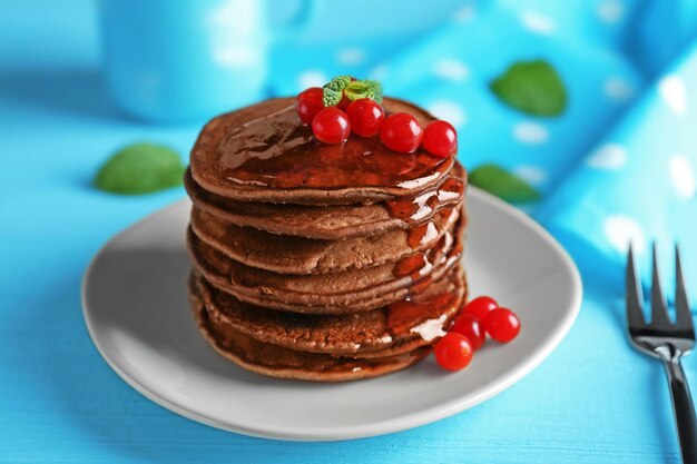 Deliciosos panqueques de chocolate con viburnum sobre mesa de madera azul