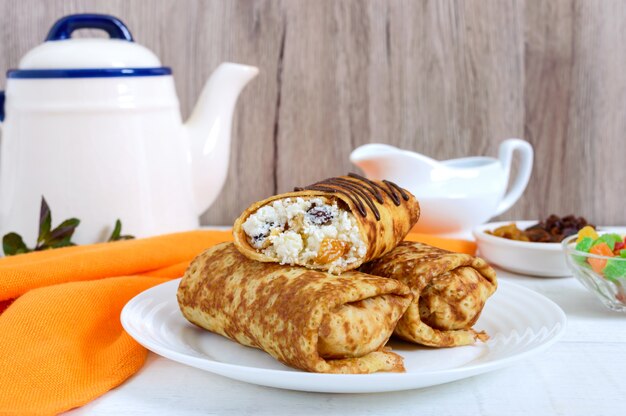 Deliciosos panqueques delicados con requesón y pasas sobre un fondo blanco de madera.