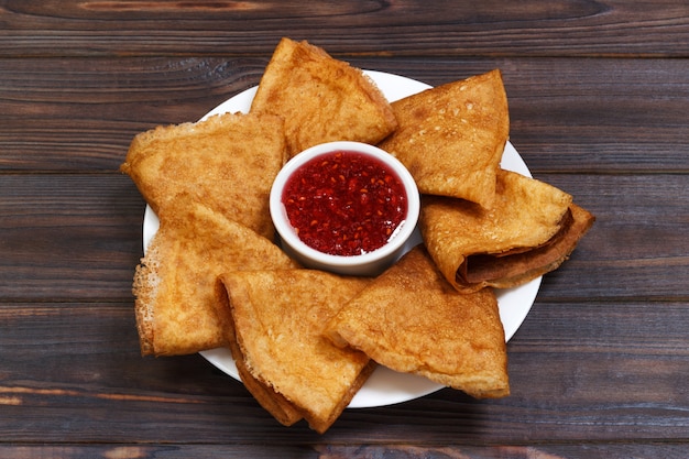 Deliciosos panqueques con frambuesas en la mesa de la cocina de madera