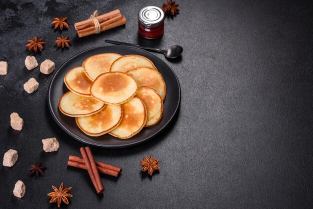 Deliciosos panqueques frescos en una tabla de cortar de madera con azúcar en un fondo de hormigón oscuro