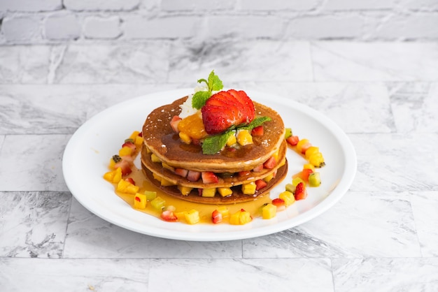 Deliciosos panqueques en mesa de mármol con frutas