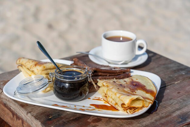 Deliciosos panqueques con miel de mangle y una taza blanca de té en la mesa de cerca