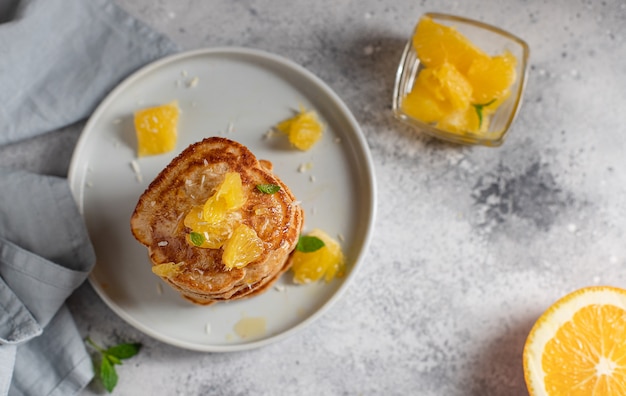 Deliciosos panqueques con naranja y menta, desayuno para toda la familia superficie de concreto gris,