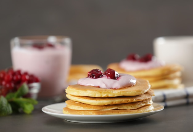 Deliciosos panqueques con yogur y bayas en la mesa