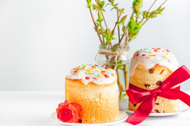 Deliciosos pasteles de Pascua decorados con cinta y flores sobre fondo blanco Comida festiva