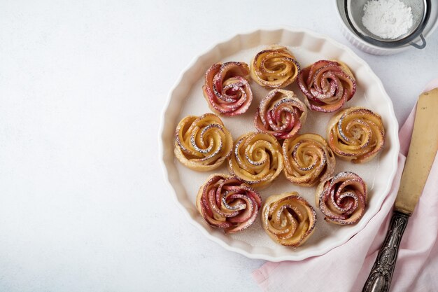 Deliciosos pasteles con una rosa de manzana en forma de cerámica sobre una superficie ligera de hormigón o piedra. Enfoque selectivo. Vista superior.