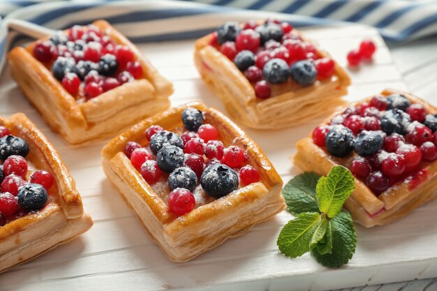 Deliciosos pasteles en la tabla de cortar de madera blanca