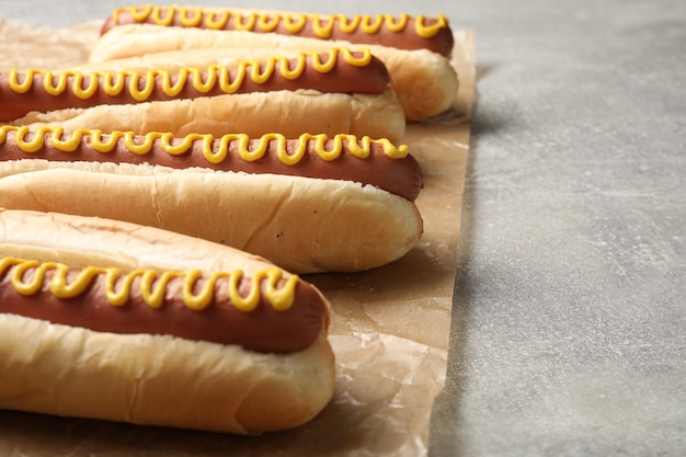 Deliciosos perritos calientes frescos con mostaza en el primer plano de la mesa gris claro Espacio para texto