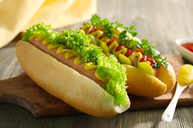 Deliciosos perritos calientes con verduras en la mesa de madera de cerca