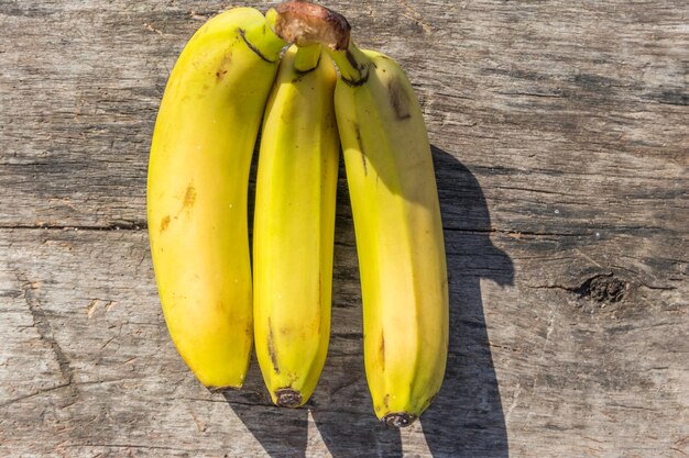 Deliciosos plátanos amarillos maduros sobre una mesa rústica de madera. Vista superior