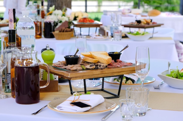 Deliciosos pratos em bandejas de madeira e drinks em mesa de banquete em restaurante luxuoso